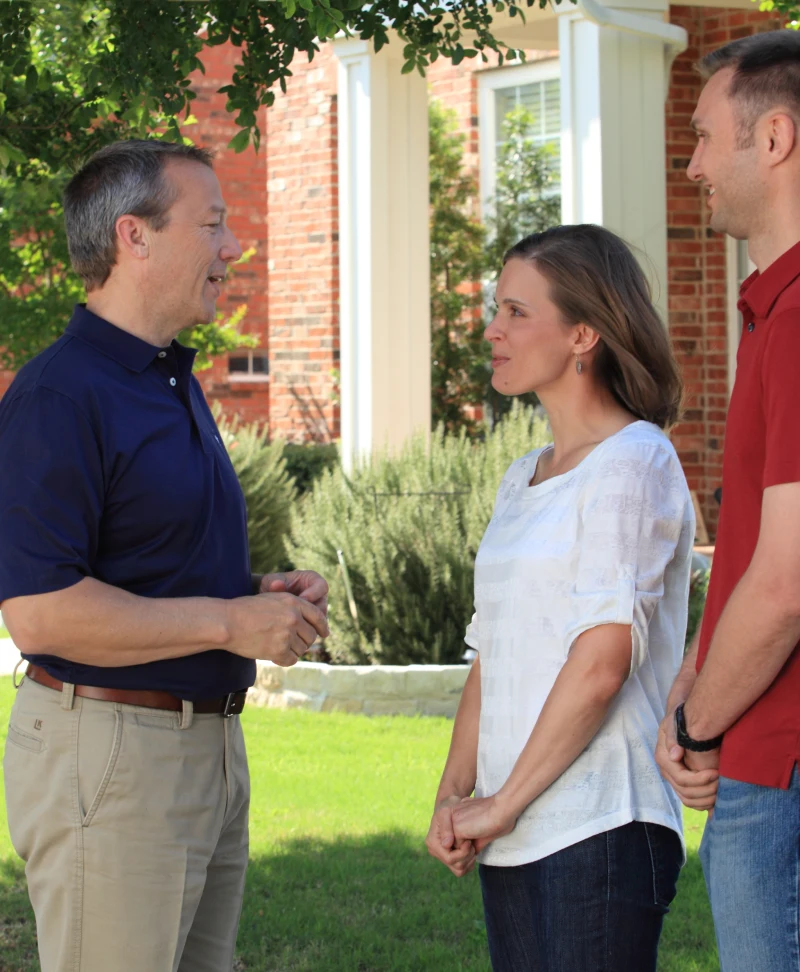 Hon. Ron Simmons speaks with two Texas residents on their front lawn.