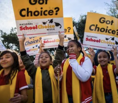 Children wearing yellow scarves and holding up posters – Ron Simmons in the press.
